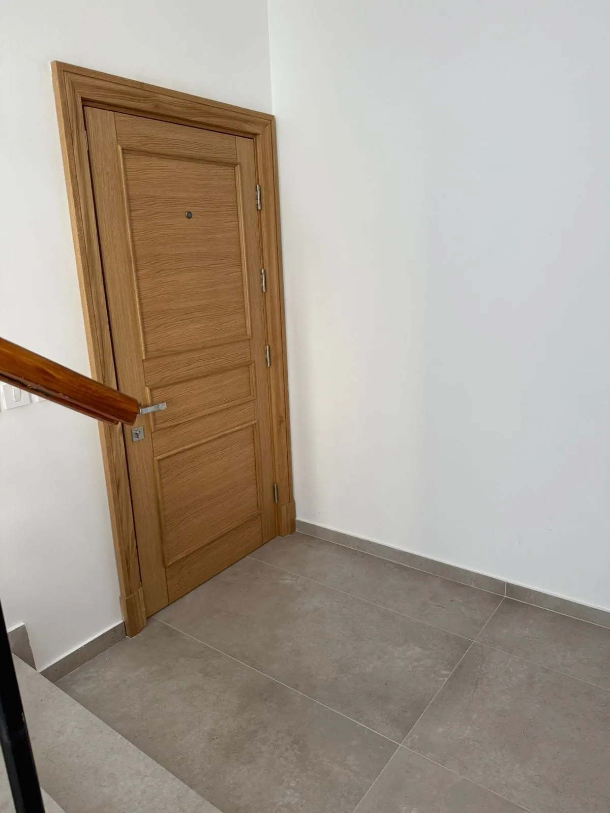 An interior door made of light wood in an apartment in Tivat, Montenegro, with porcelain tile flooring.