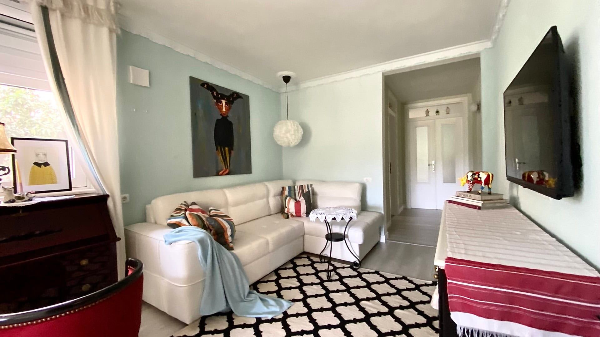 Cozy living room with a white corner sofa in an apartment for sale, Petrovac, Montenegro. Modern interior with a TV.