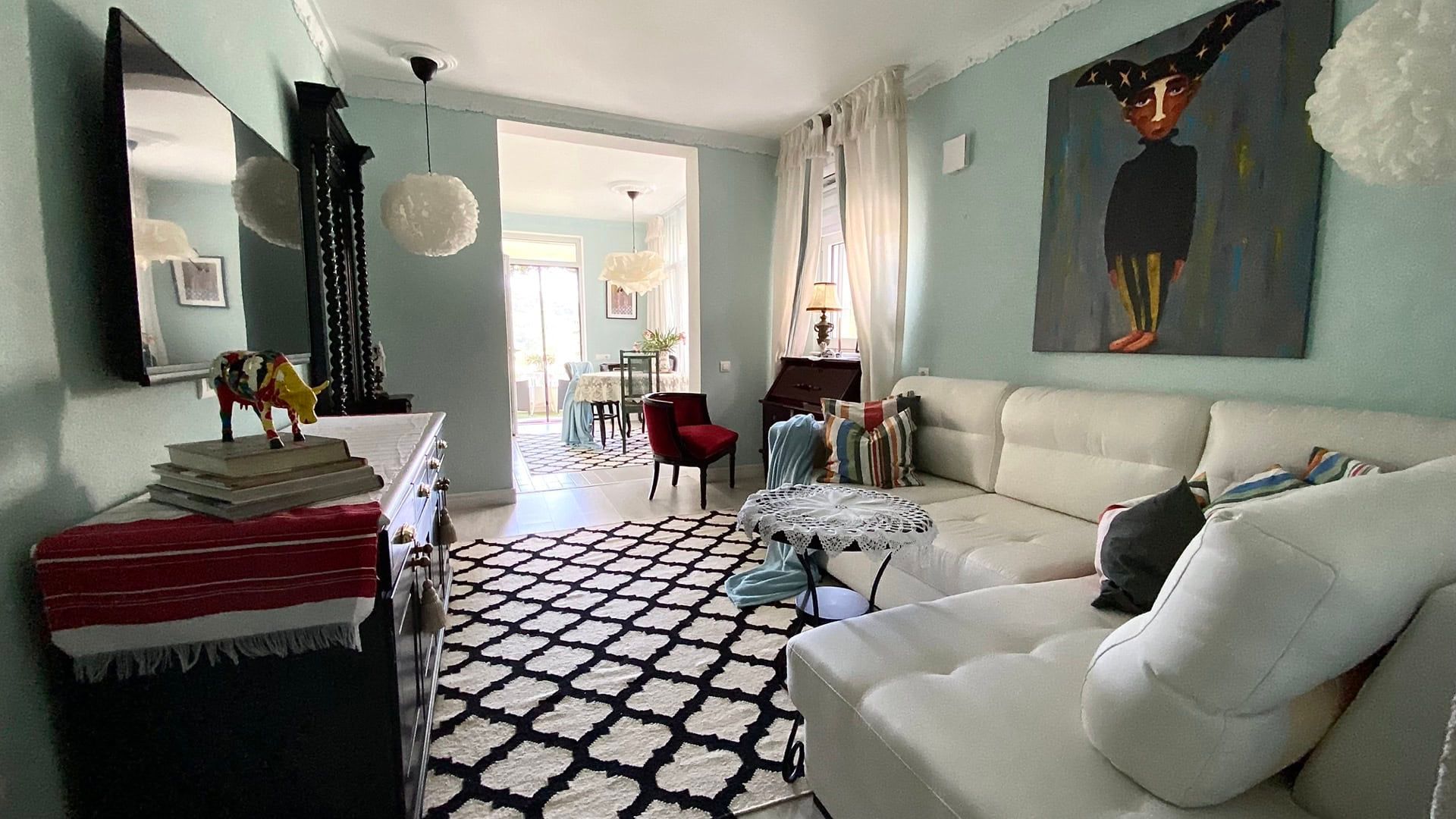 Bright living room with a white sofa in an apartment in Petrovac, Montenegro: stylish interior with a painting and access to the terrace