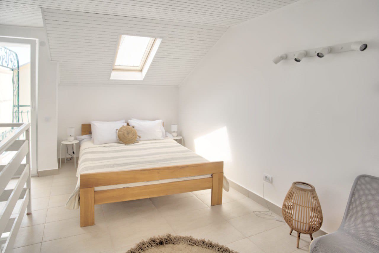 Bright bedroom in a duplex in Baošići, Montenegro: wooden bed, skylight, and modern interior.