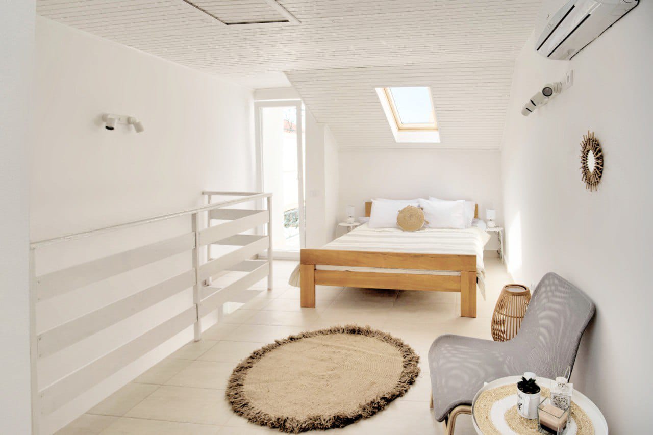 Bright bedroom in a duplex in Baošići, Montenegro: wooden bed, skylight, and modern interior.