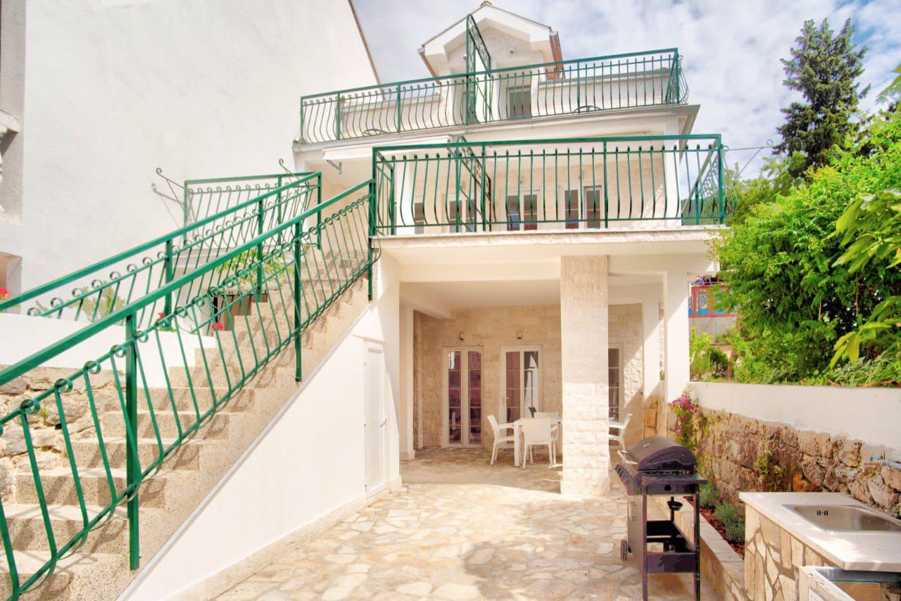Two-story house in Baošići, Montenegro: terrace with grill, stone finish, exterior staircase, and balcony with railing.