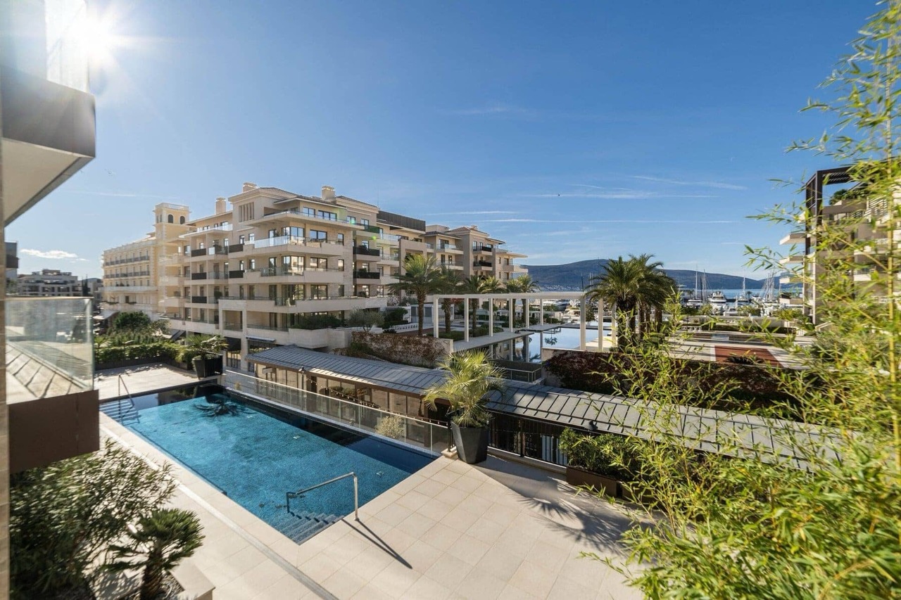 Pogled na otvoreni bazen i luksuzni stambeni kompleks u Porto Montenegru, Tivat, Crna Gora, sa terase apartmana.