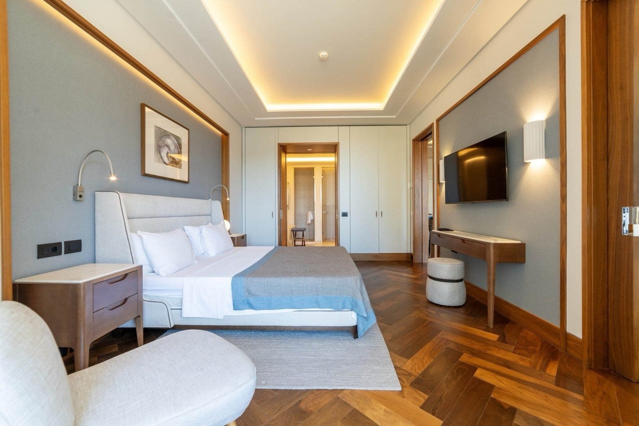 Savremena spavaća soba u stanu Porto Montenegro, Tivat, Crna Gora: bračni krevet, parket i dizajnersko osvetljenje.