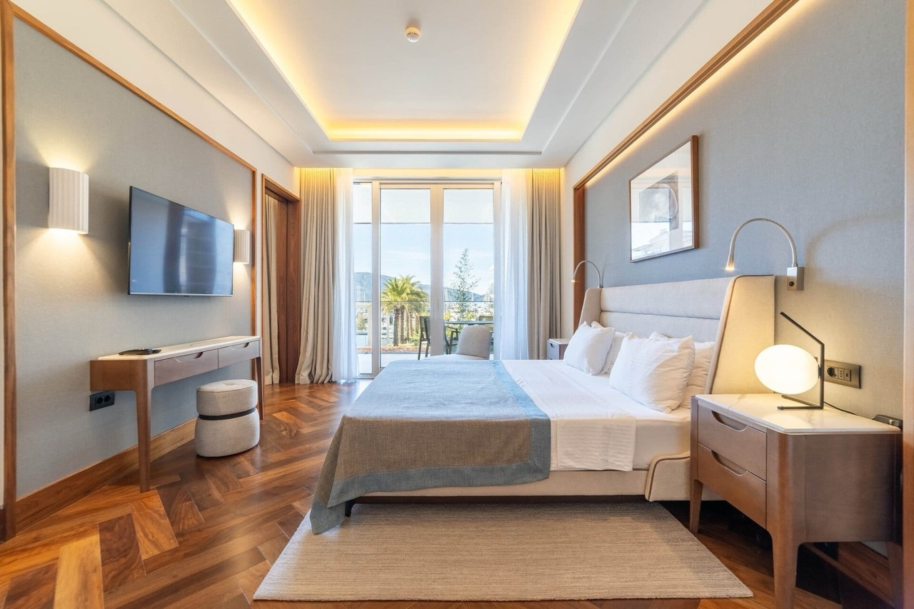 Savremena spavaća soba u stanu Porto Montenegro, Tivat, Crna Gora: bračni krevet, parket i pogled na marinu.