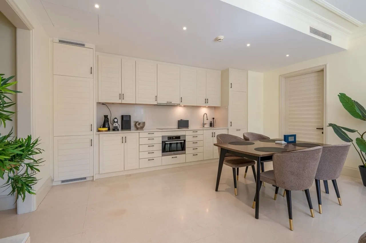 Moderne Küche in einer Wohnung in Porto Montenegro, Tivat, Montenegro: helle Einbauküche und Essbereich mit Stühlen.