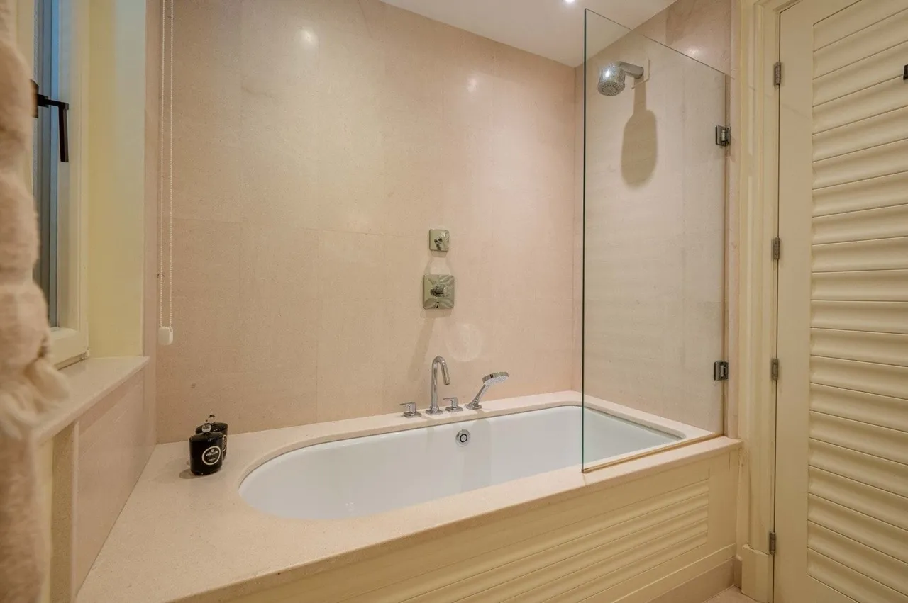Badezimmer in einer Wohnung in Porto Montenegro, Tivat, Montenegro: eingebaute Badewanne mit Verkleidung aus beigem Stein.