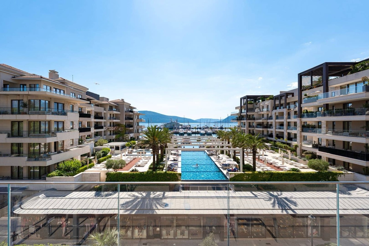 Вид на элитный жилой комплекс Porto Montenegro в Тивате, Черногория: бассейн, яхтенная марина и террасы квартир.