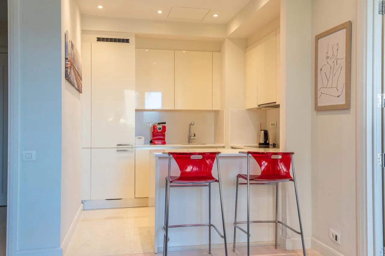 Moderne Küche in einer Wohnung in Porto Montenegro, Tivat, Montenegro: helle Einbauküche und leuchtend rote Barhocker.