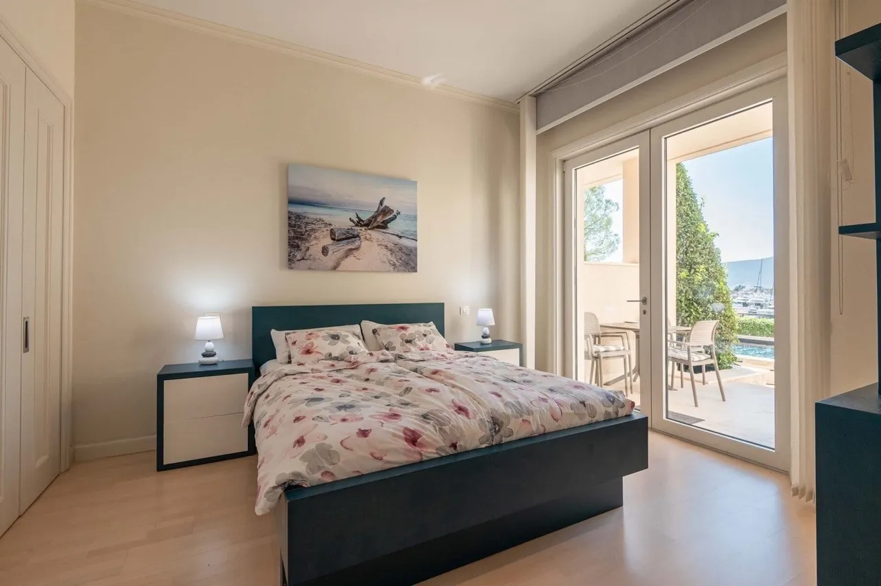 Schlafzimmer in einer Wohnung in Porto Montenegro, Tivat, Montenegro: Doppelbett, Zugang zur Terrasse mit Blick auf den Yachthafen.