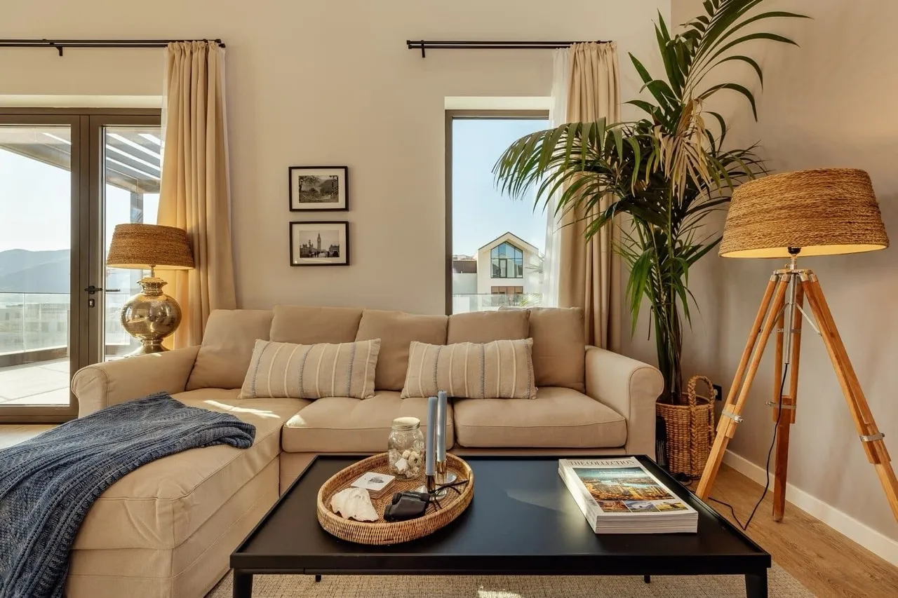 Gemütliches Wohnzimmer mit Sofa, Couchtisch, Stehlampe und Topfpalme.