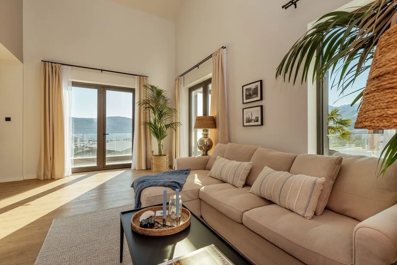 Geräumiges Wohnzimmer mit einem beigen Sofa, Panoramafenstern und Meerblick.