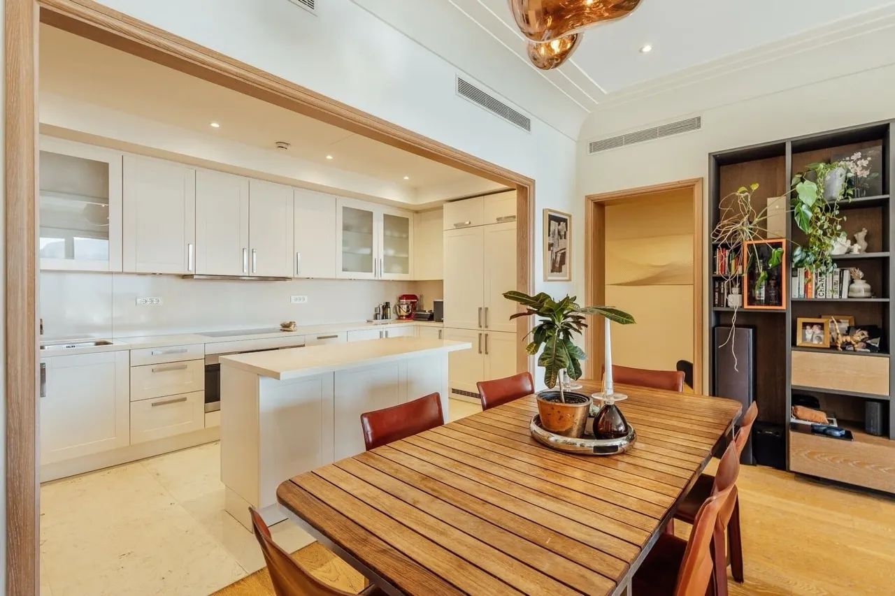 Cuisine-salle à manger moderne dans un appartement à Porto Montenegro, Tivat, Monténégro : mobilier clair, îlot et table à manger.