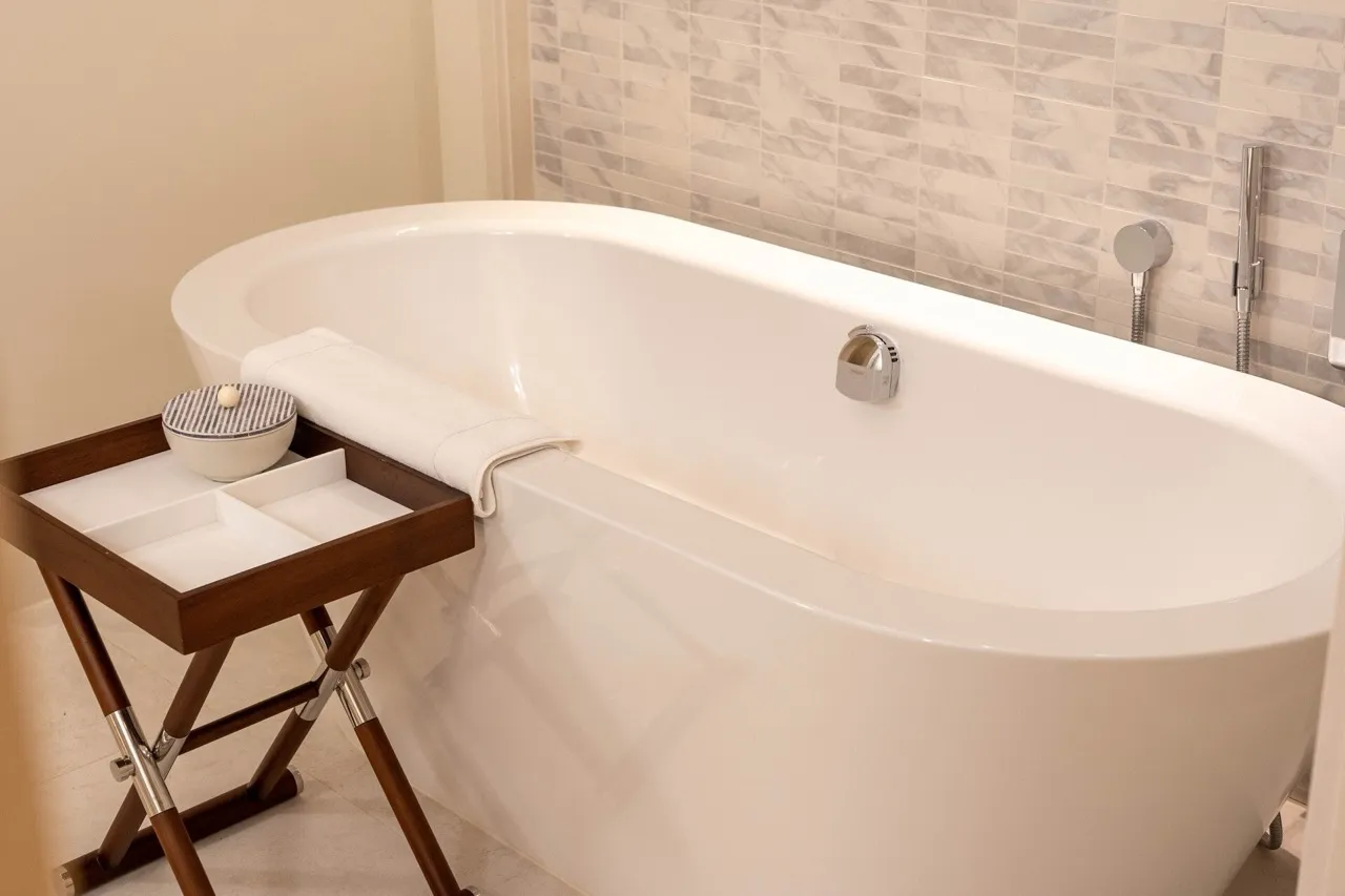 Modernes Badezimmer mit weißer ovaler Badewanne und Fliesenverkleidung in einer Wohnung in Tivat, Montenegro.