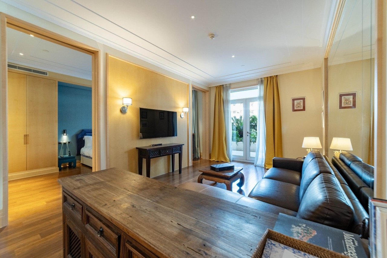 Dnevna soba u apartmanima Porto Montenegro, Tivat, Crna Gora: kožna sofa, drveni nameštaj i izlaz na terasu.