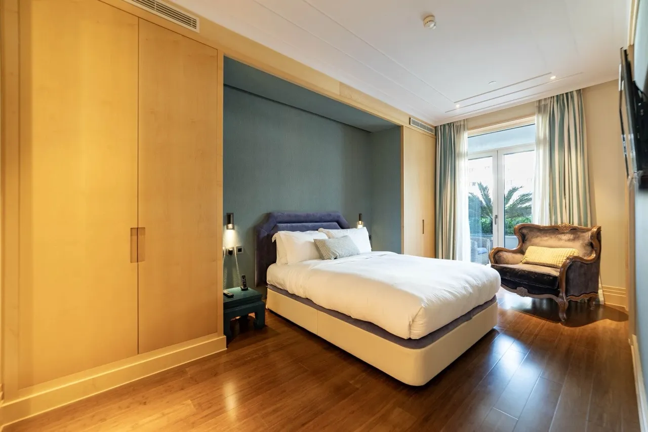 Bedroom in an apartment in Porto Montenegro, Tivat, Montenegro: double bed, wooden wardrobes, and an armchair by the window.