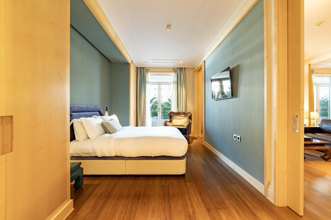 Savremena spavaća soba u apartmanima Porto Montenegro, Tivat: bračni krevet, drveni pod i pogled na terasu.