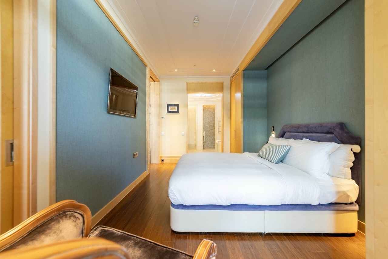 Savremena spavaća soba sa bračnim krevetom u stanu Porto Montenegro, Tivat, Crna Gora. Enterijer sa plavim zidovima.
