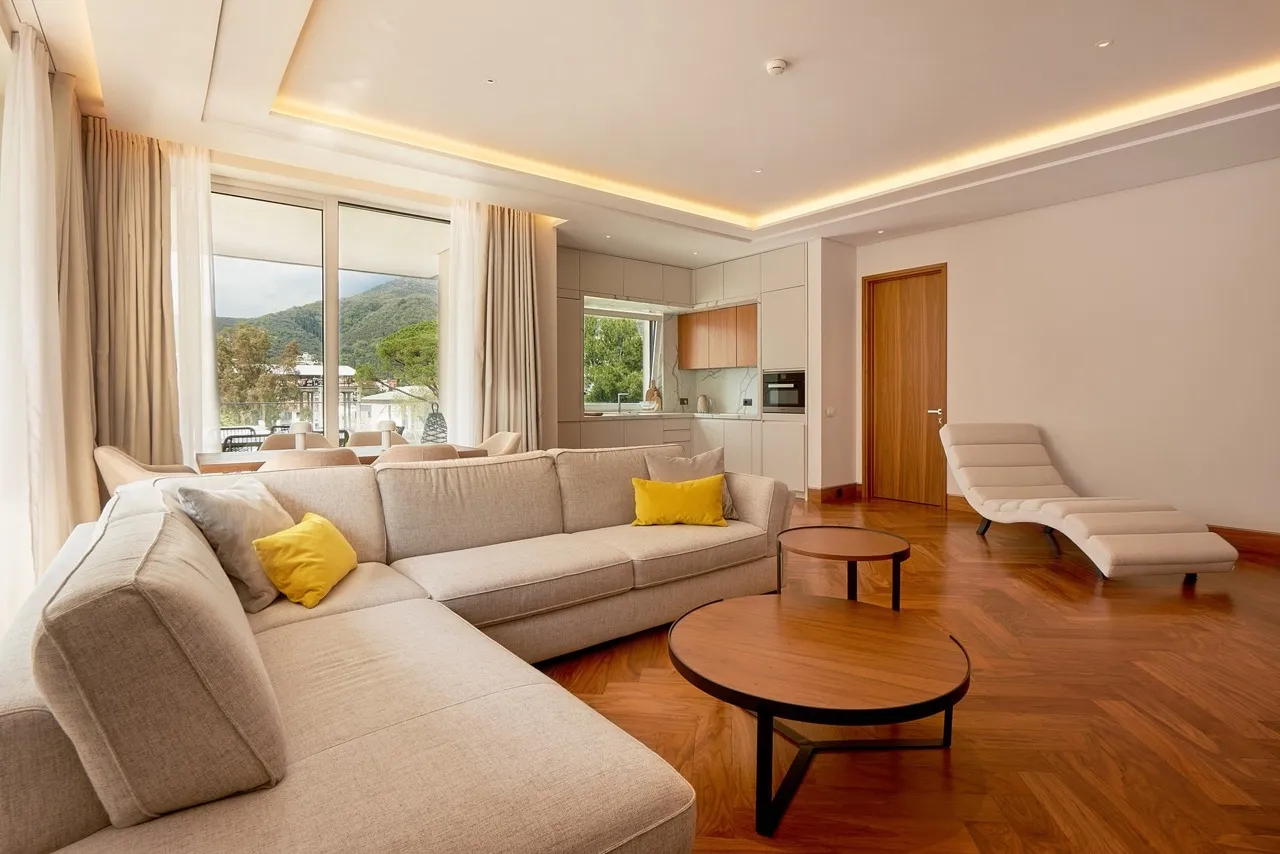 Modernes Wohnzimmer mit Küche in Porto Montenegro, Tivat, Montenegro: helle Möbel, Parkett und Bergblick.