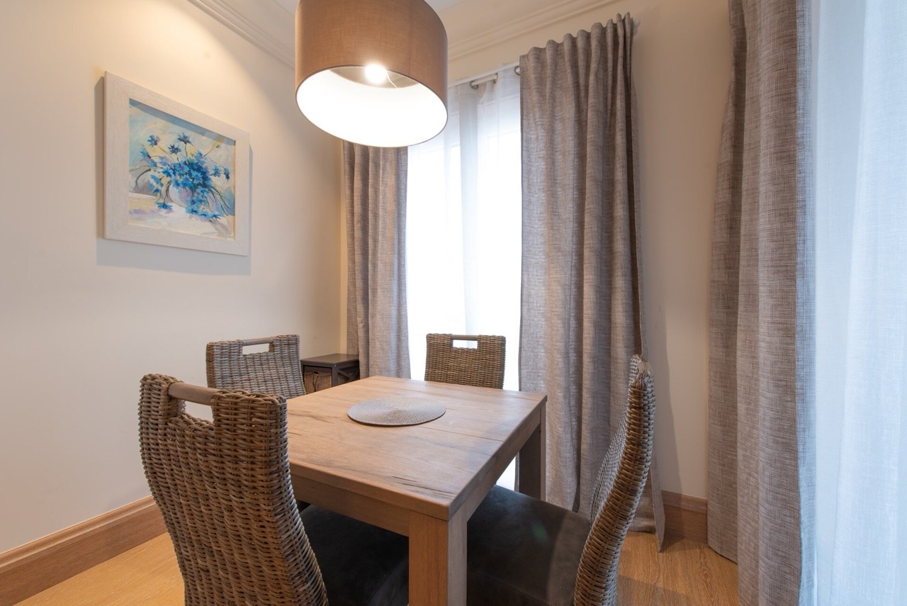 Trpezarijski deo sa drvenim stolom i pletenim stolicama u stanu Porto Montenegro, Tivat, Crna Gora.