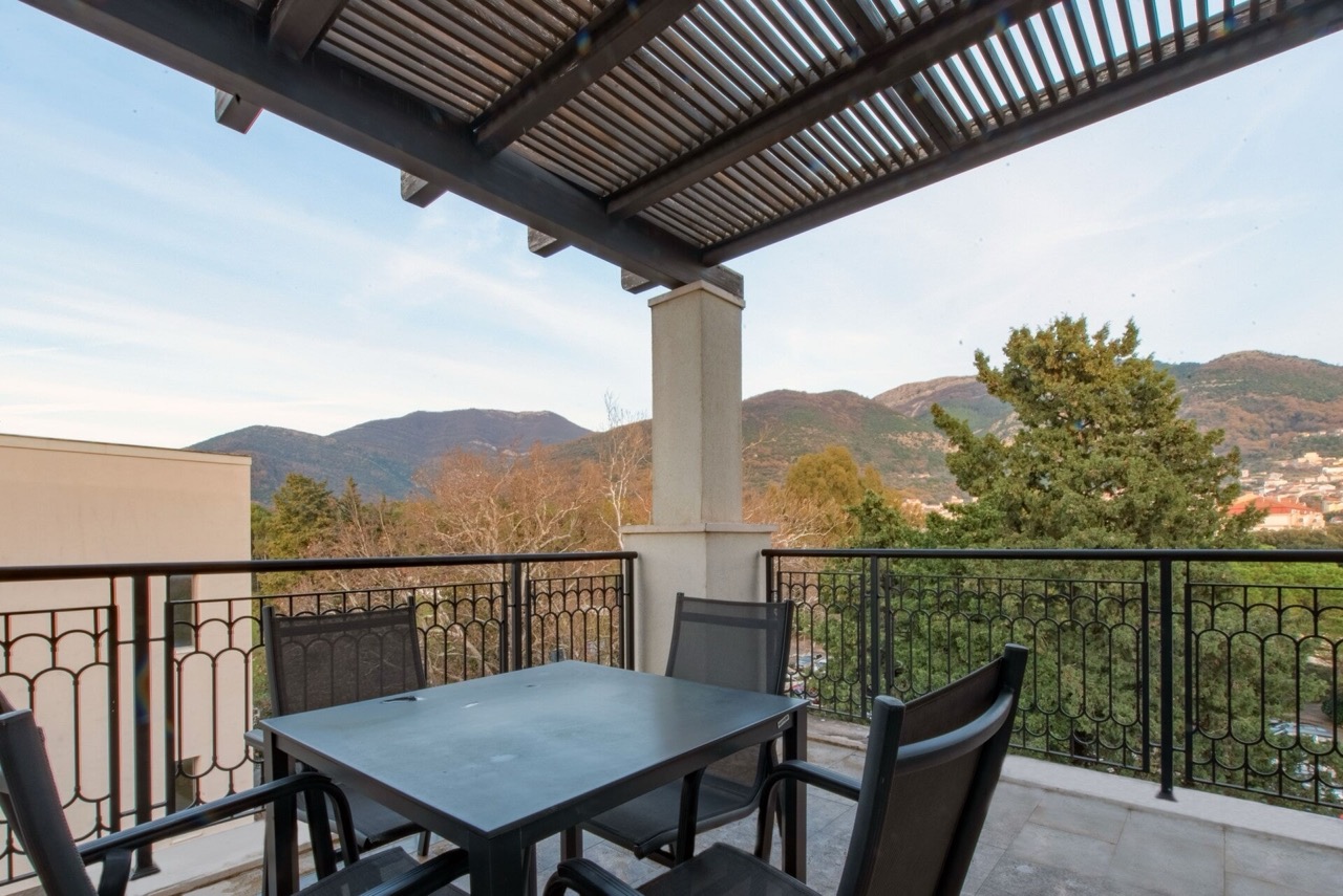 Terasa sa nameštajem i pogledom na planine u stanu Porto Montenegro, Tivat, Crna Gora. Balkon sa nadstrešnicom i kovanom ogradom.