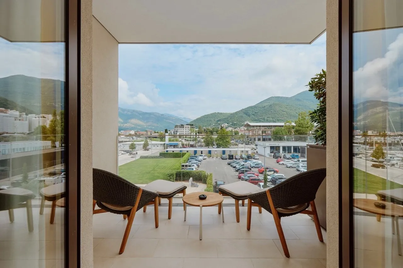 Blick vom Balkon der Wohnung in Porto Montenegro, Tivat, Montenegro: Rattanmöbel und Panoramablick auf die Berge und die Marina.