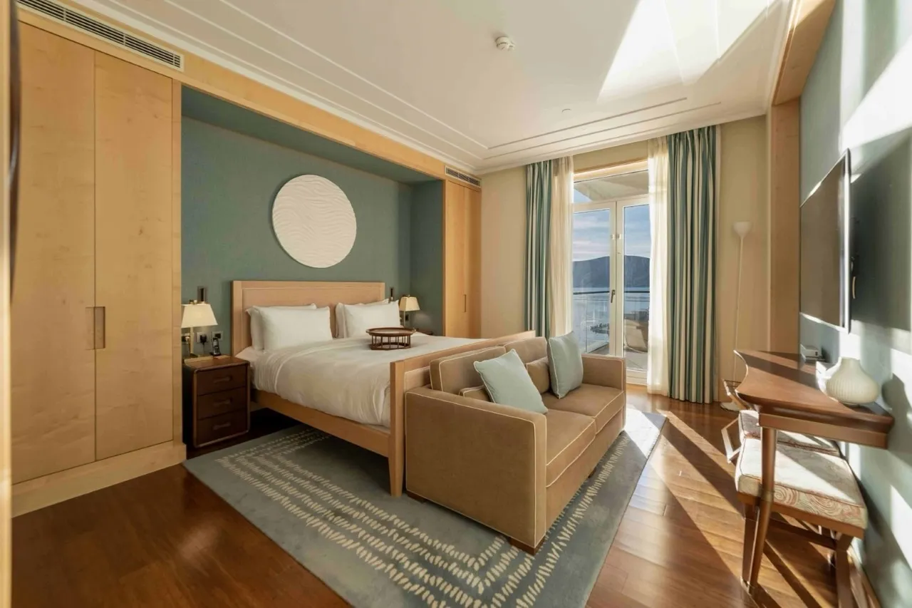 Schlafzimmer in den Apartments von Porto Montenegro, Tivat, Montenegro: Doppelbett, Sofa und Meerblick von der Terrasse.