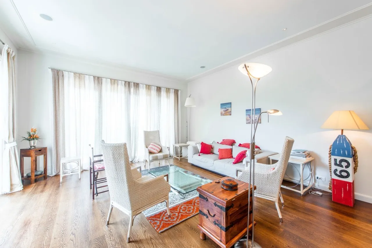 Helles Wohnzimmer in einer Wohnung in Porto Montenegro, Tivat, Montenegro: geflochtene Sessel, Sofa mit roten Kissen, Dekor.