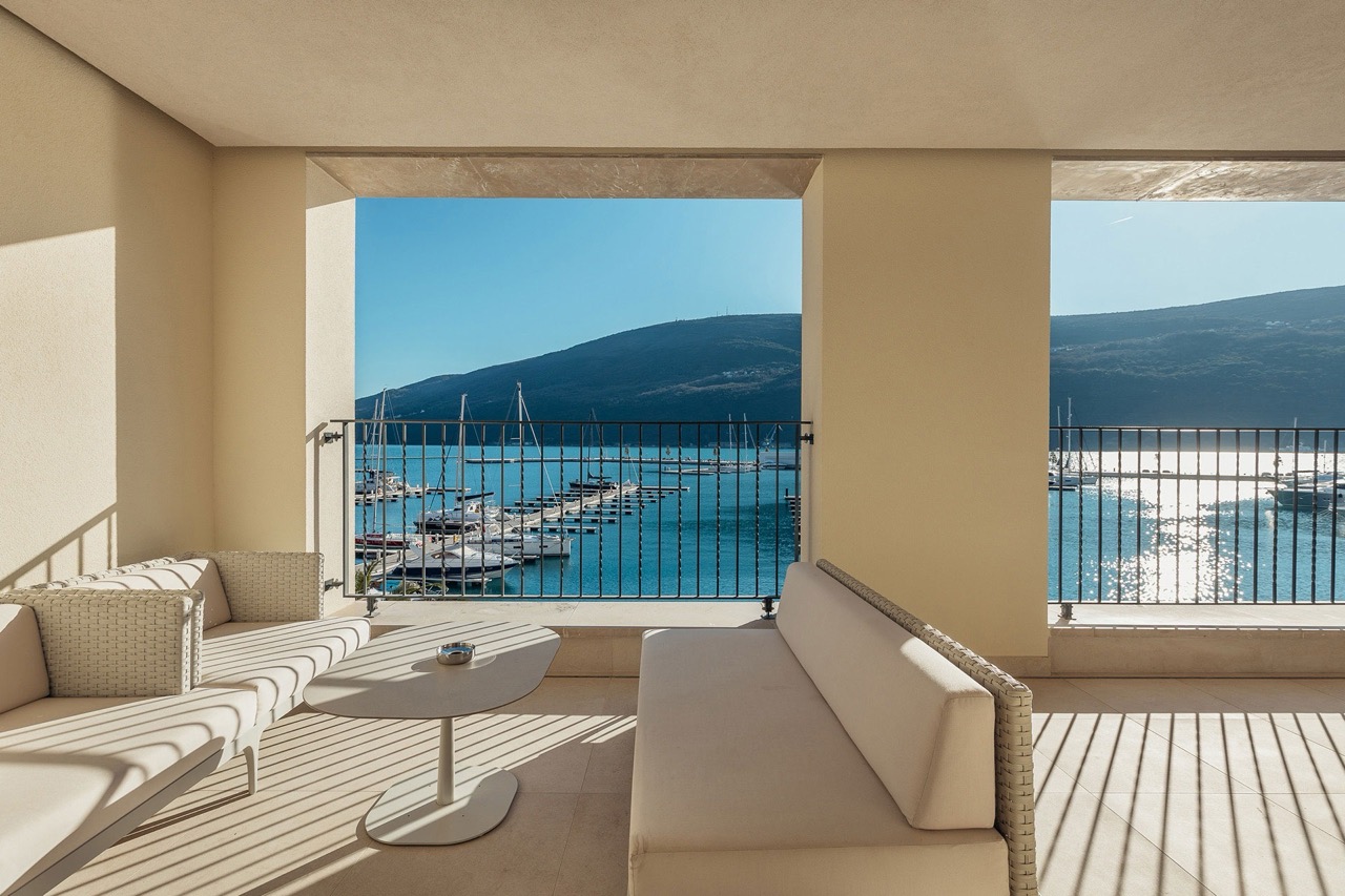 Terrasse mit geflochtenen Möbeln und Blick auf die Marina Portonovi, Kumbor, Montenegro. Moderne Wohnung mit Panoramablick.