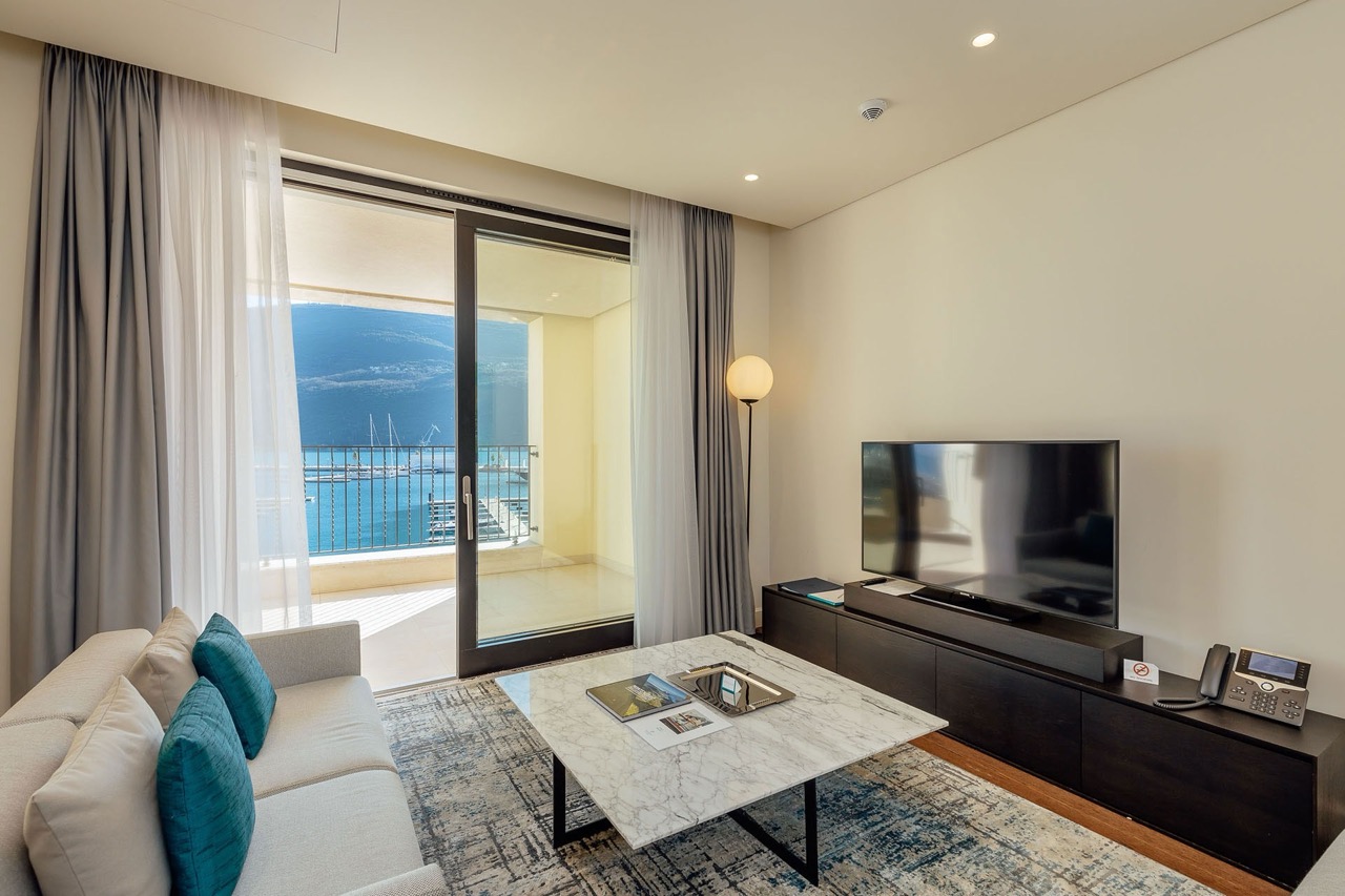 Wohnzimmer in den Portonovi-Apartments, Kumbor, Montenegro: moderne Möbel, Marmortisch und Blick auf den Yachthafen mit Yachten.