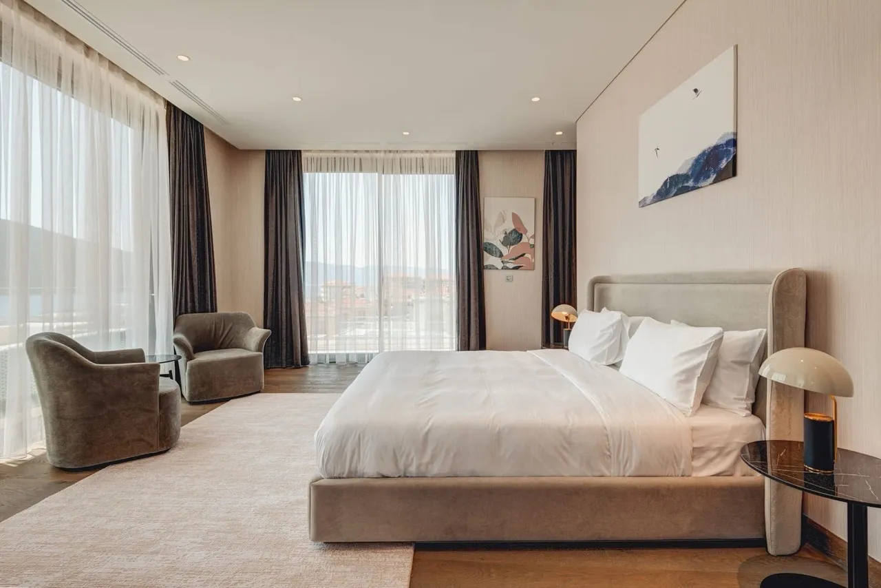 Modern bedroom in an apartment in Portonovi, Kumbor, Montenegro: double bed, panoramic windows, and sea view.