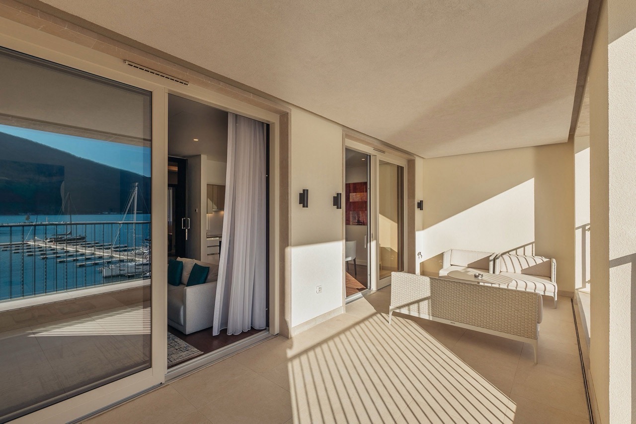 Geräumige Terrasse mit Rattanmöbeln und Blick auf die Marina Portonovi, Kumbor, Montenegro. Wohnung mit Panoramafenstern.
