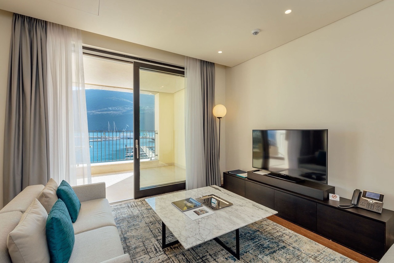 Wohnzimmer in der Wohnung Portonovi, Kumbor, Montenegro: Blick auf die Marina, Marmortisch, Sofa und moderne Möbel.
