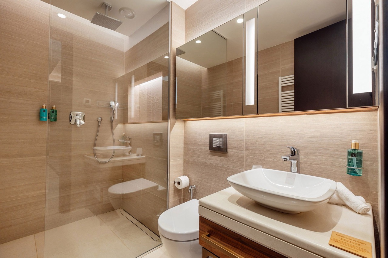 Modernes Badezimmer in einer Wohnung in Portonovi, Kumbor, Montenegro: Glasdusche, Aufsatzwaschbecken und Beleuchtung.
