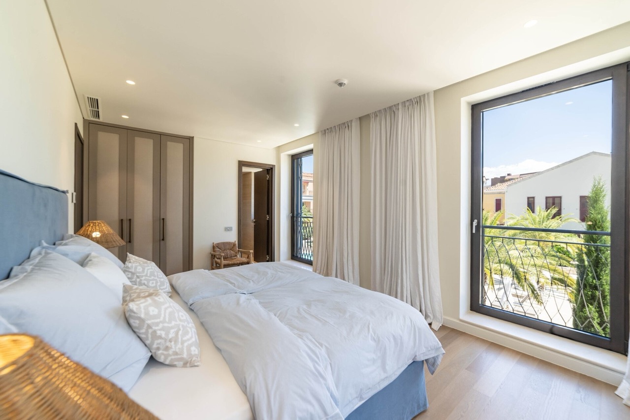 Modernes Schlafzimmer in der Wohnung Portonovi, Kumbor, Montenegro: Doppelbett, Einbauschrank und Blick auf Palmen.