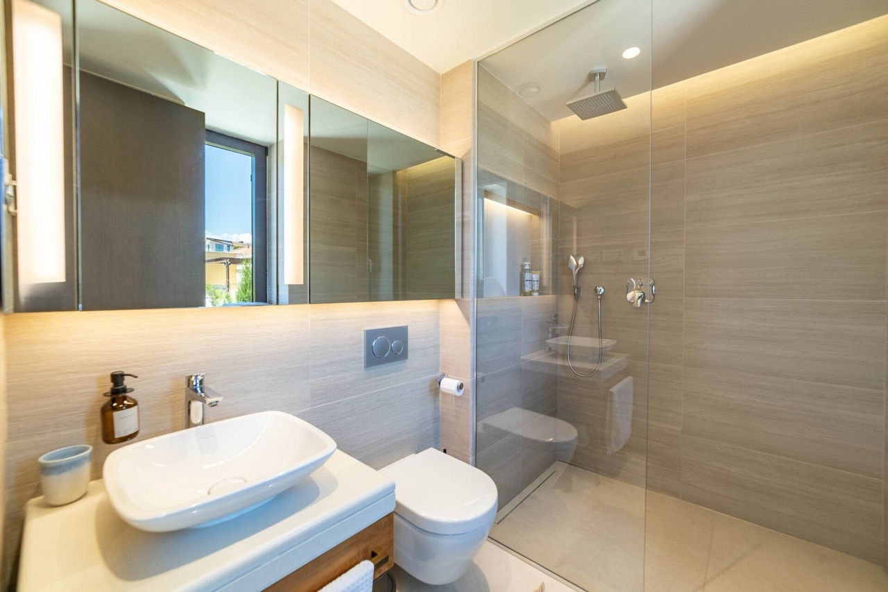 Modernes Badezimmer in der Wohnung Portonovi, Kumbor, Montenegro: Duschkabine, Aufsatzwaschbecken und Beleuchtung.