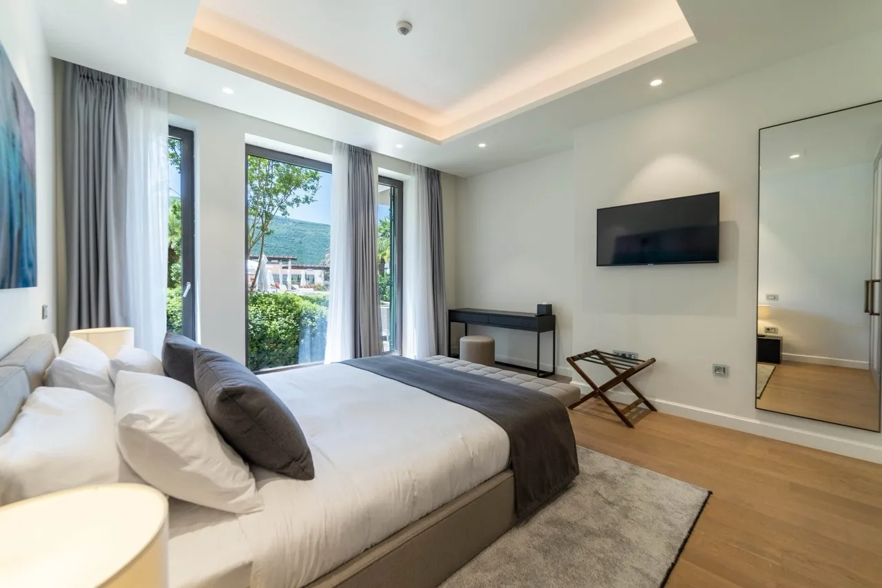 Modernes Schlafzimmer in der Wohnung Portonovi, Kumbor, Montenegro: Doppelbett, Panoramafenster und Blick auf den Garten.