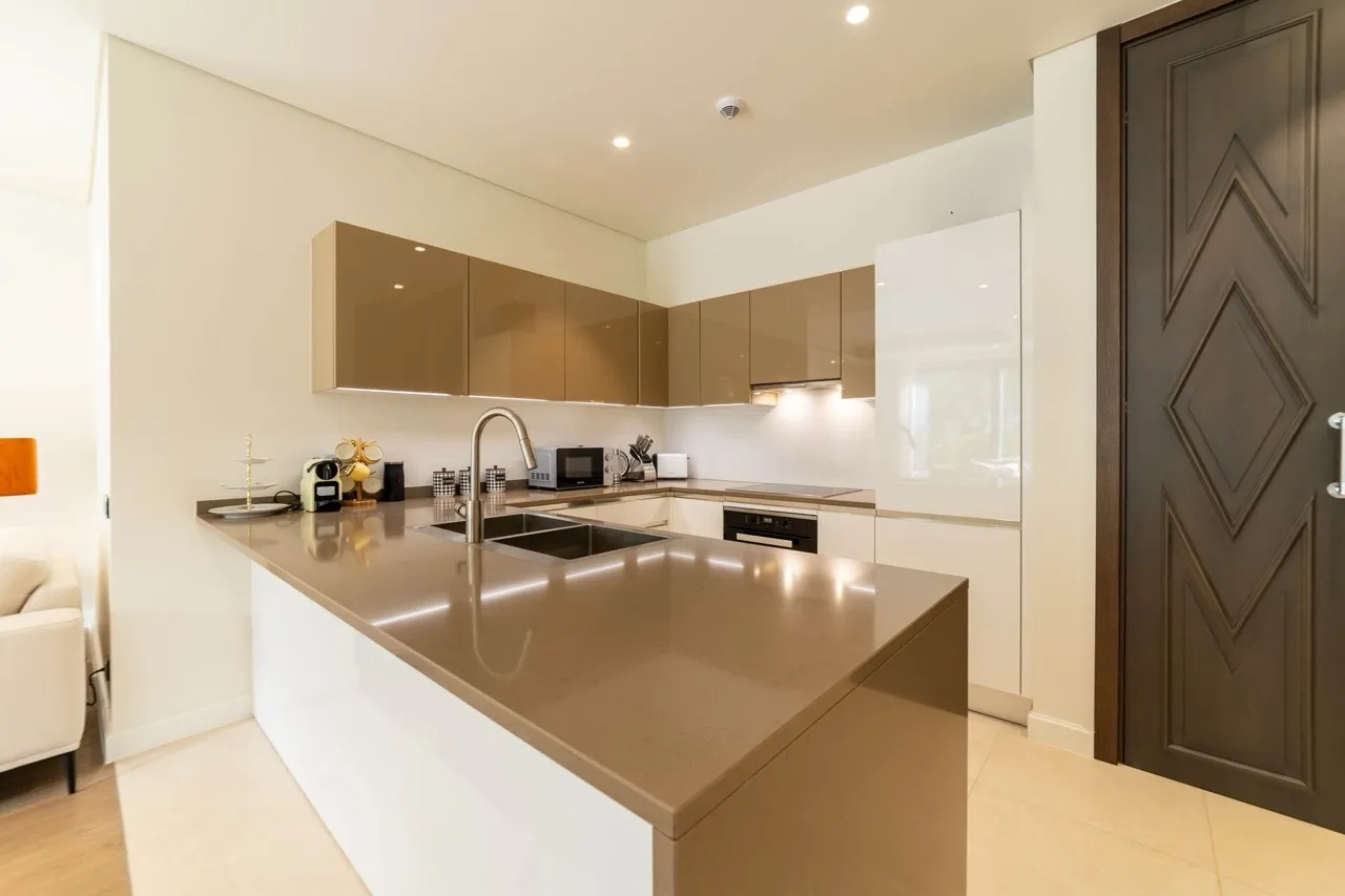 Nowoczesna кухня z wyspą w apartamencie Portonovi, Kumbor, Czarnogóra: błyszczące fronty, wbudowany sprzęt i design.