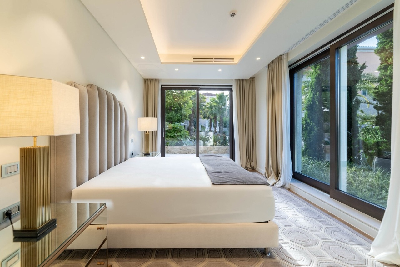 Modernes Schlafzimmer in der Wohnung Portonovi, Kumbor, Montenegro: Doppelbett, Panoramafenster und Blick auf den Garten.