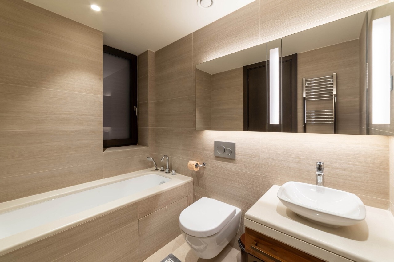 Modernes Badezimmer mit beiger Ausstattung in der Wohnung Portonovi, Kumbor, Montenegro: Badewanne, Waschbecken und Beleuchtung.
