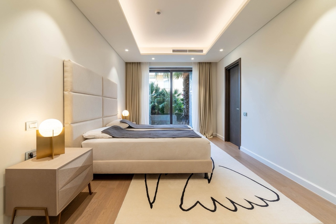 Modernes Schlafzimmer in der Wohnung Portonovi, Kumbor, Montenegro: Doppelbett, Designer-Teppich und Blick auf den Garten.