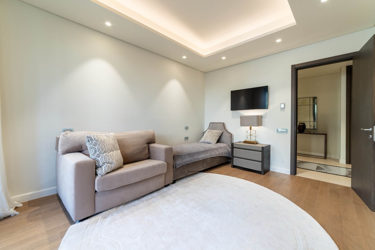 Modernes Schlafzimmer in der Wohnung Portonovi, Kumbor, Montenegro: beiges Sofa, Bett, TV und stilvolle Beleuchtung.