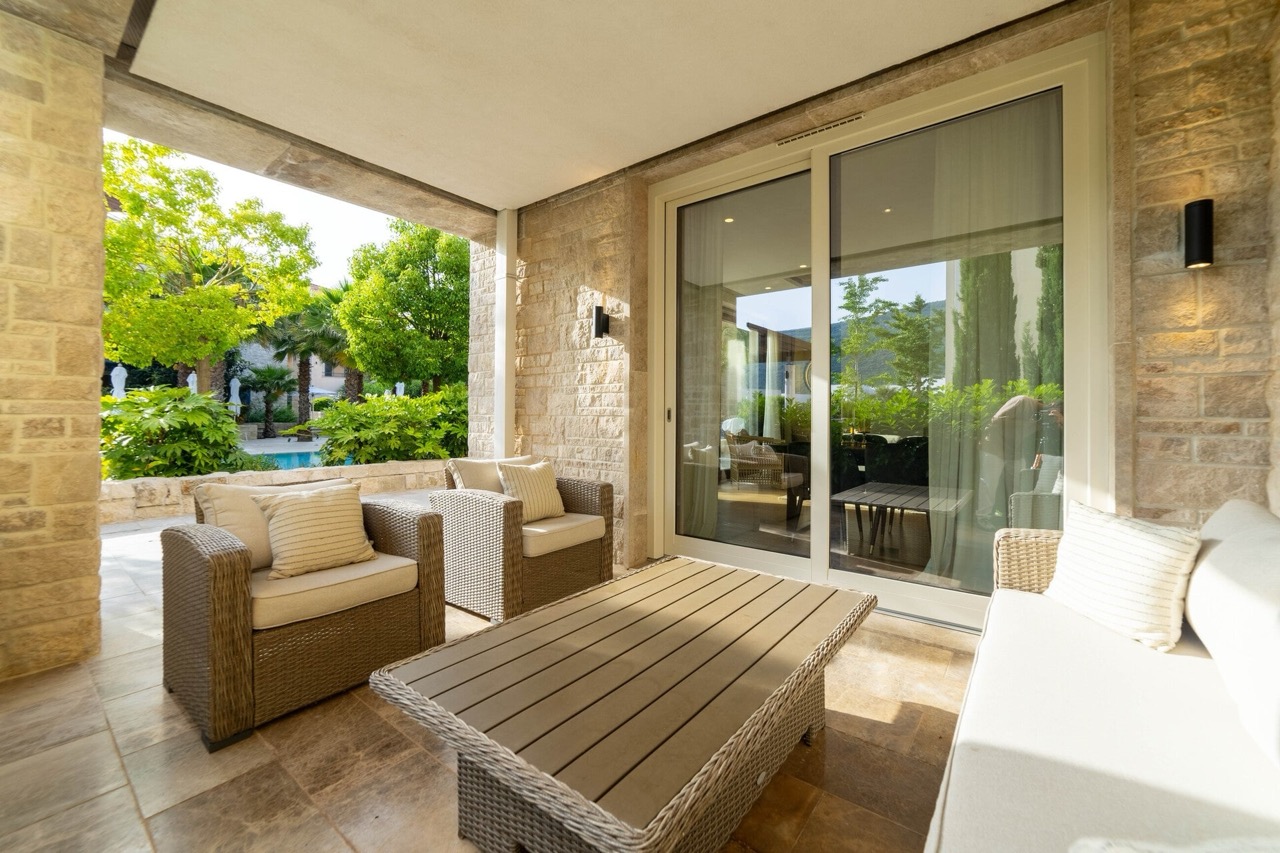 Gemütliche Terrasse mit Rattanmöbeln und Blick auf den Garten in der exklusiven Wohnanlage Portonovi, Kumbor, Montenegro.