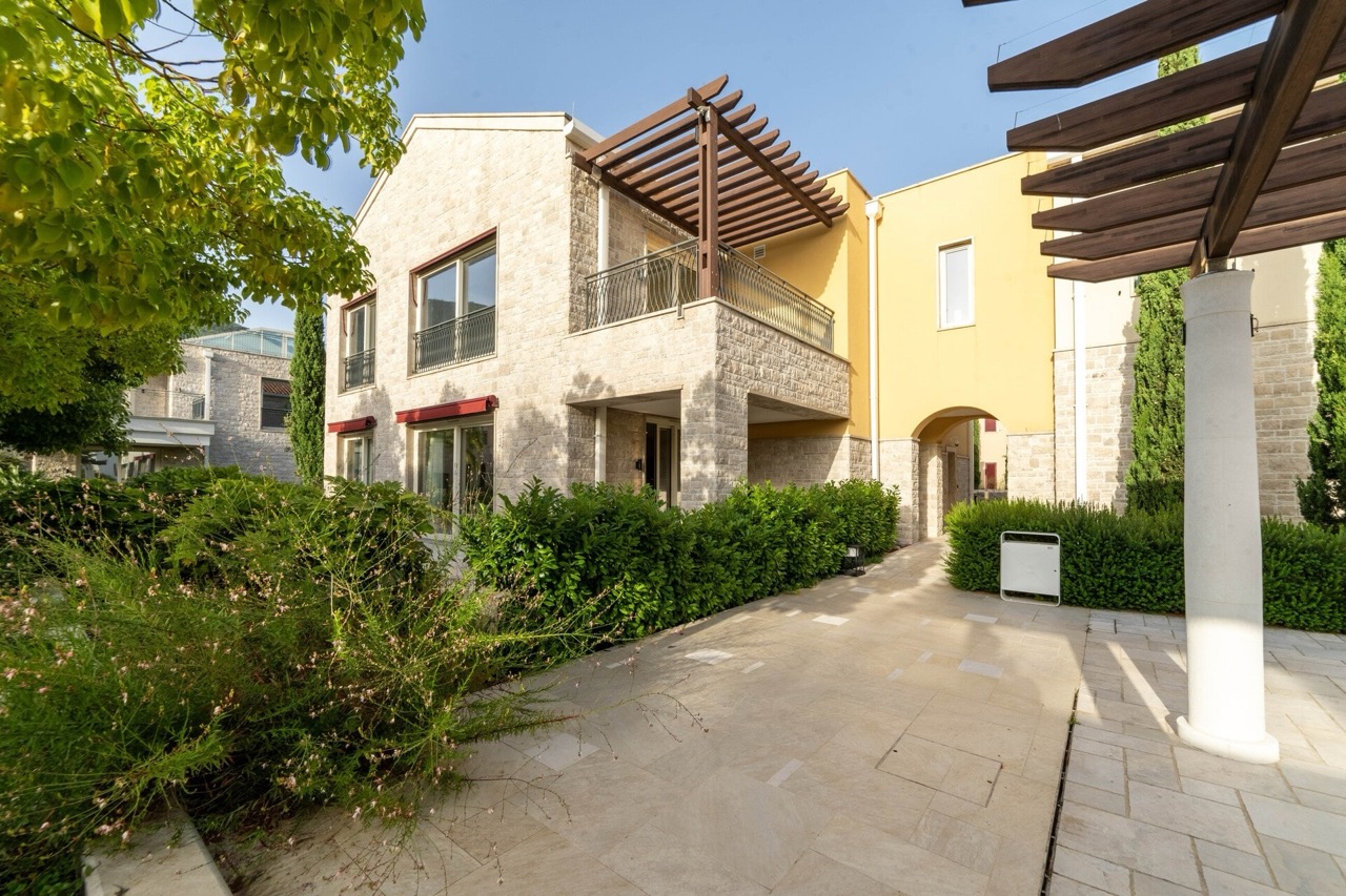 Fassade einer modernen Wohnung in Portonovi, Kumbor, Montenegro: Steinverkleidung, Terrasse mit Pergola und gepflegter Garten.