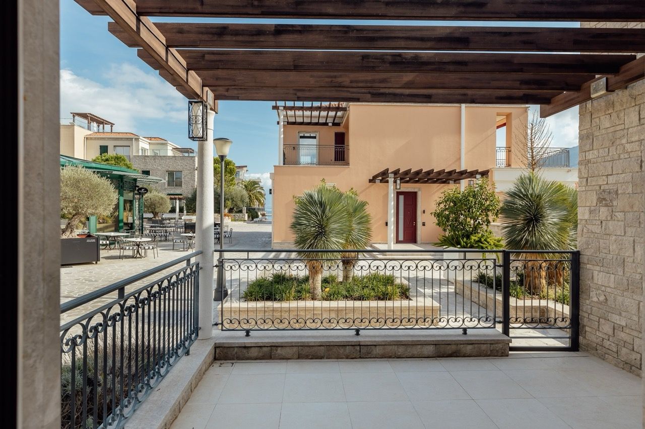 Villa balcony in Portonovi, Kumbor, Montenegro: view of the landscaped grounds with a pergola, palm trees, and stone finishes.