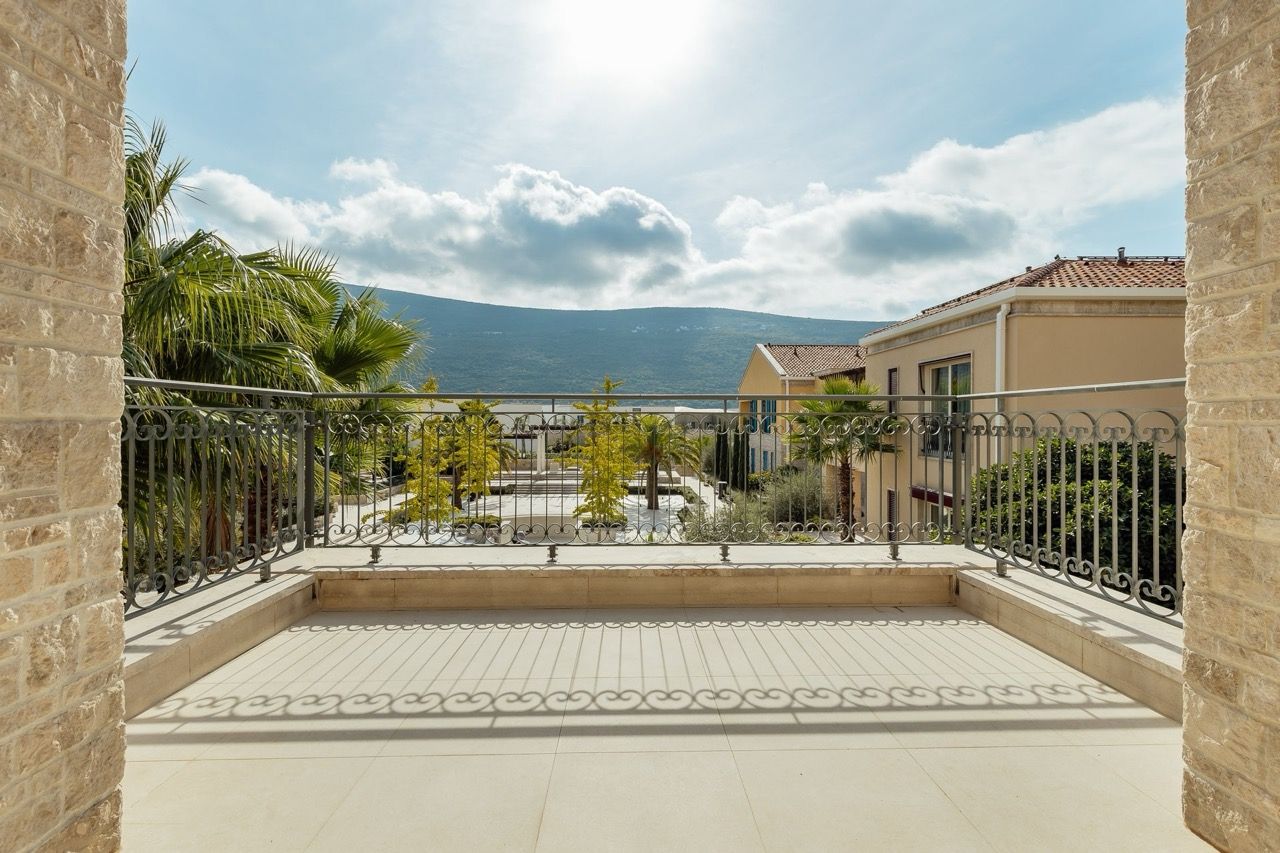 View from the stone terrace of a villa in Portonovi, Kumbor, Montenegro: a panorama of mountains, garden, and Mediterranean architecture.