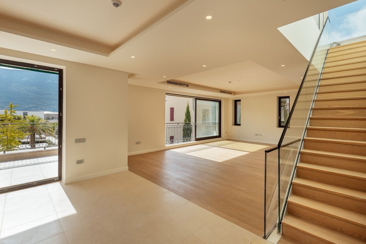 Spacious living room with a wooden staircase and panoramic windows in a villa in Portonovi, Kumbor, Montenegro.
