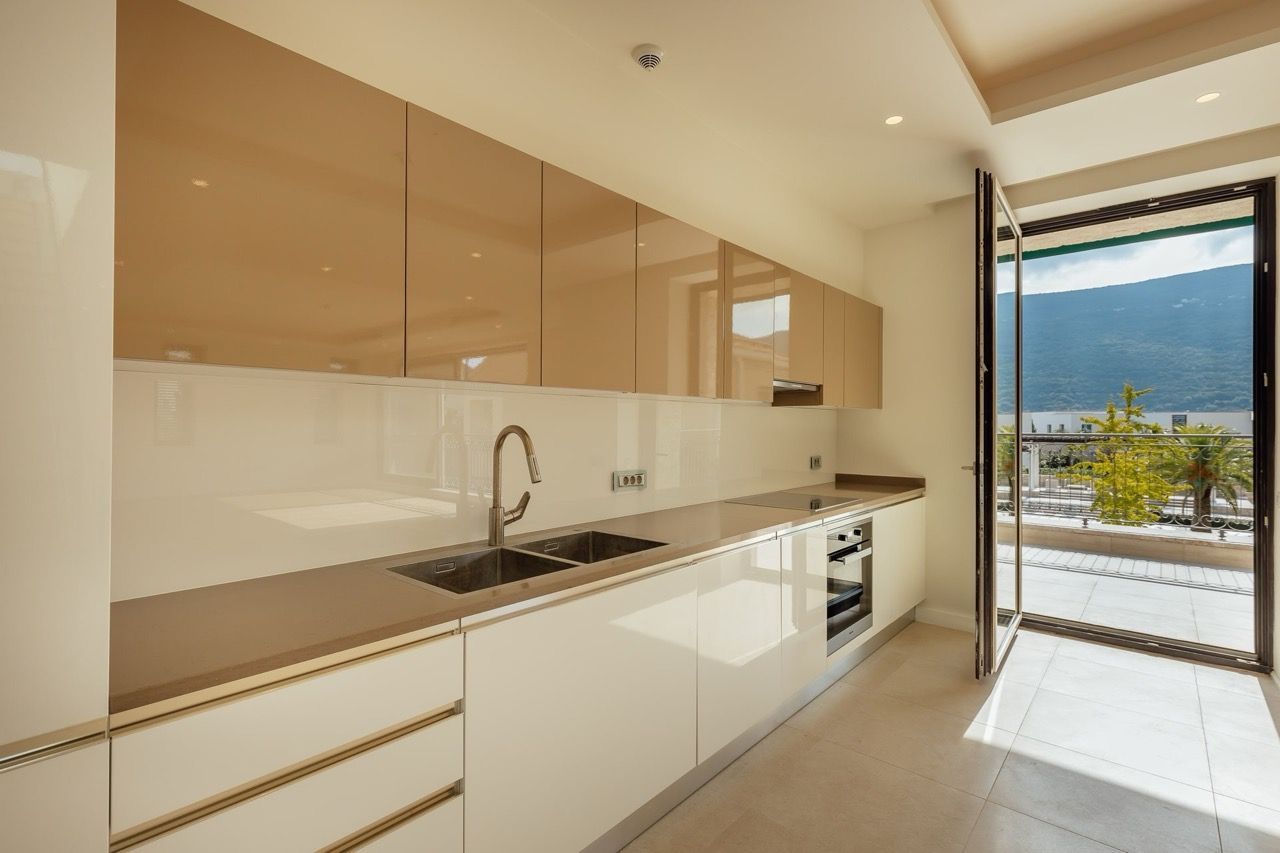 Modern kitchen in a villa in Portonovi, Kumbor, Montenegro: glossy cabinets, built-in appliances, and access to the terrace.