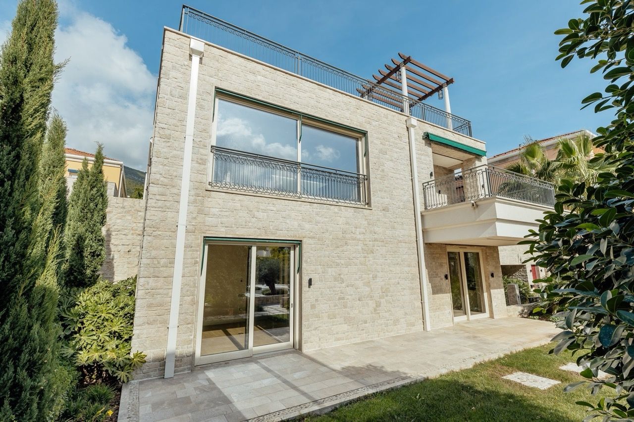 Two-story villa in Kumbor, Montenegro: stone facade, panoramic windows, rooftop terrace, and a well-kept garden.