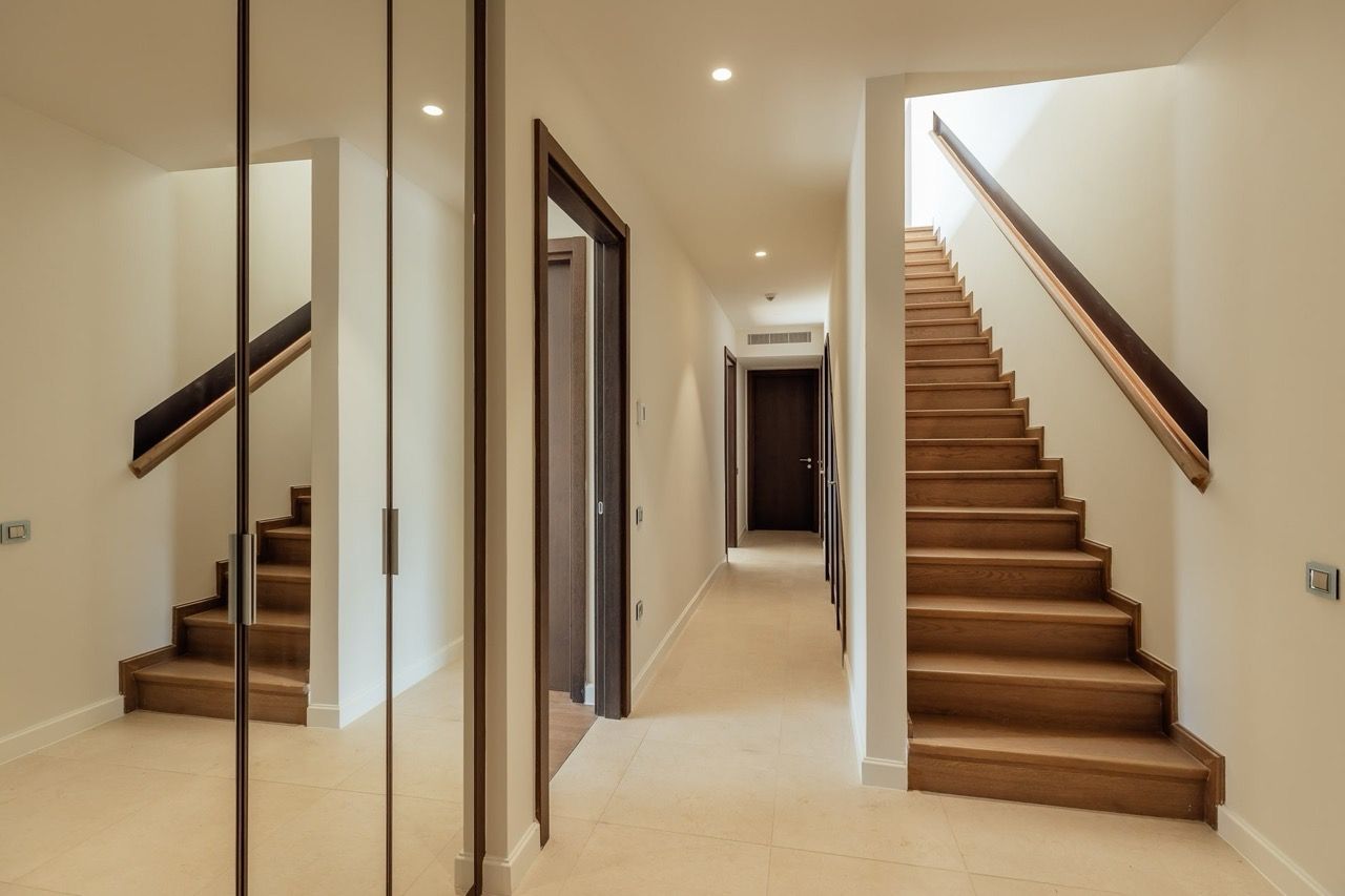 Modern villa interior in Portonovi, Kumbor, Montenegro: a bright hallway with a wooden staircase and mirrored wardrobe.